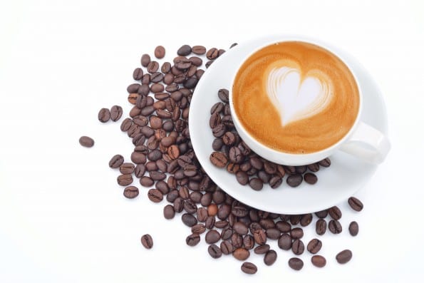 A cup of cafe latte and coffee beans on white