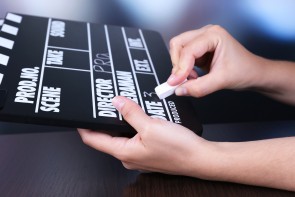 Black cinema clapper board in hands, close up