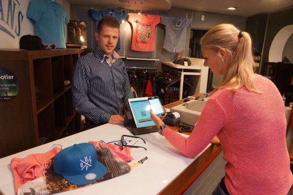 Een klant rekent af met DigiBytes bij Michael Hauser van House of Jeans in Zoetermeer. Met de 'wallet' op haar telefoon scant ze de QR-code op de tablet van de winkel. Ze drukt op OK: klaar! De toonbank herkent automatisch de goederen die er op liggen. Foto: Peter de Ruiter