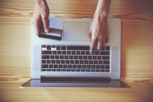 46650893 - hands holding credit card and using laptop. view from above