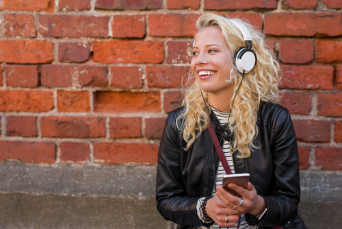 Vrolijke vrouw luistert naar muziek op telefoon