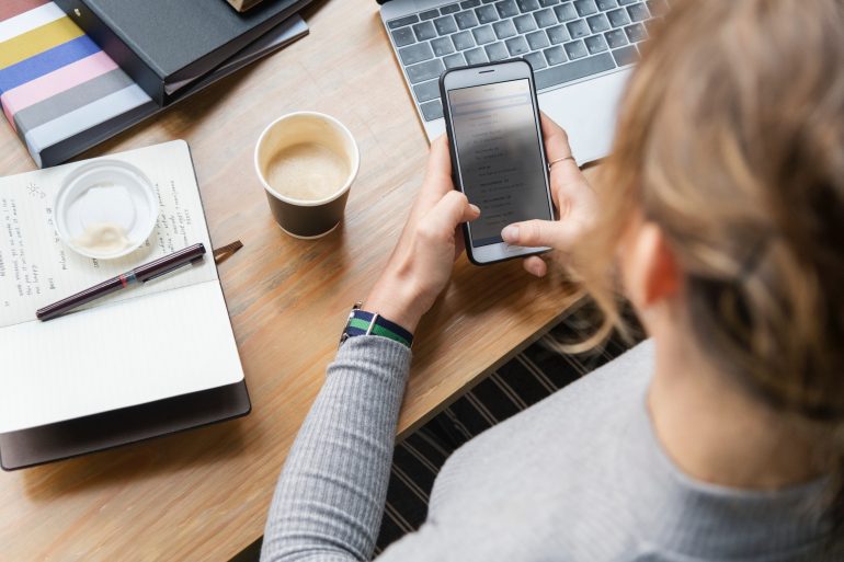 Een vrouw bekijkt een e-mail op haar smartphone.
