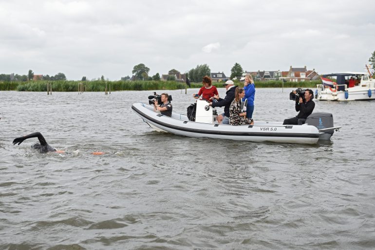 Maarten van der Weijden tijdens de 11stedenzwemtocht in 2018 met achter hem de persboot.