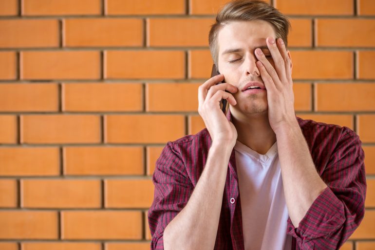 man wacht aan de telefoon moe