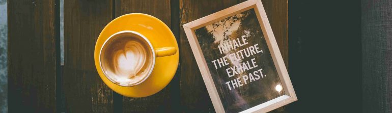 Afbeelding van een kop koffie met een notitie: Inhale the future, exhale the past.