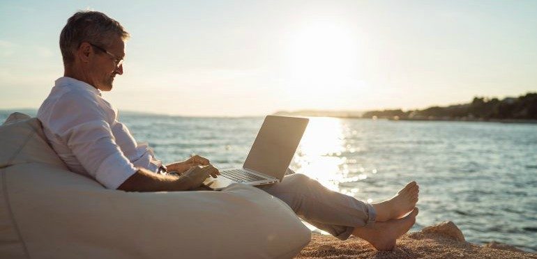 Foto van iemand die op het strand aan het werk is. Een slecht voorbeeld van slimmer werken.