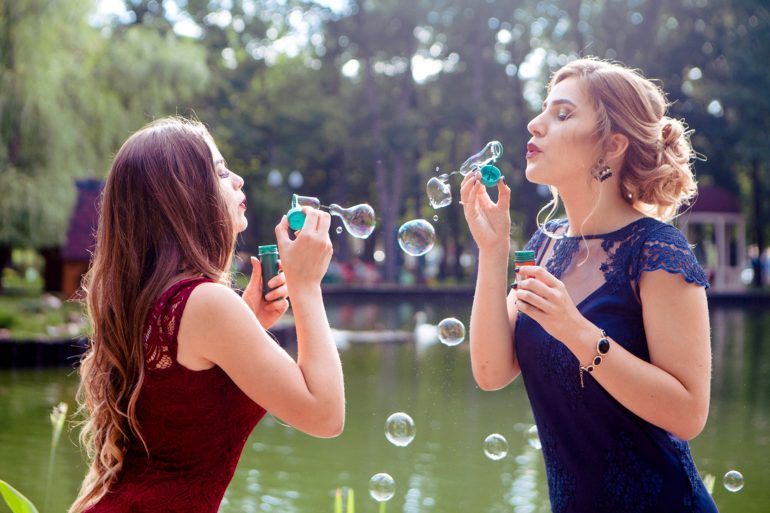 Foto van twee vrouwen die bellen blazen naar elkaar