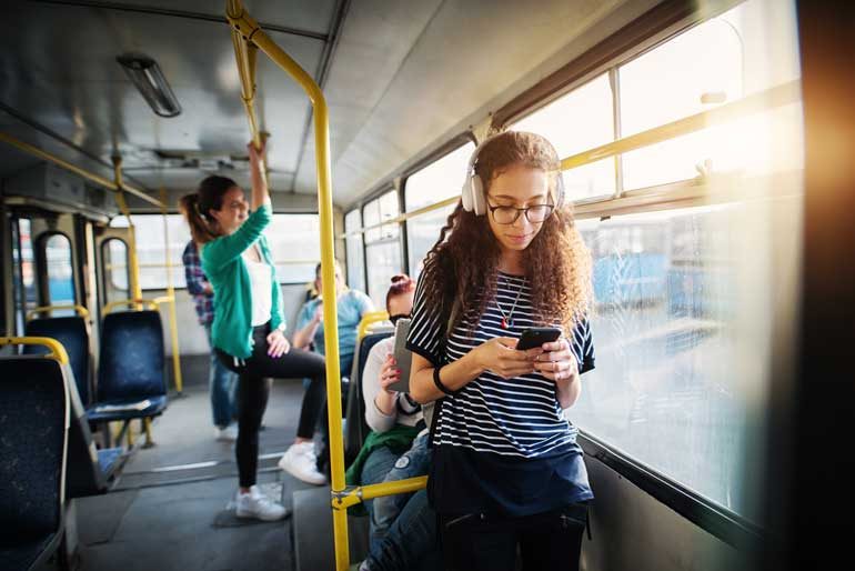 Vrouw luistert podcast in bus.