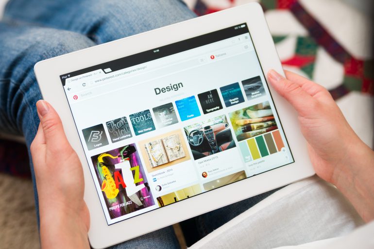 Iemand die op de tablet kijkt naar design op Pinterest.