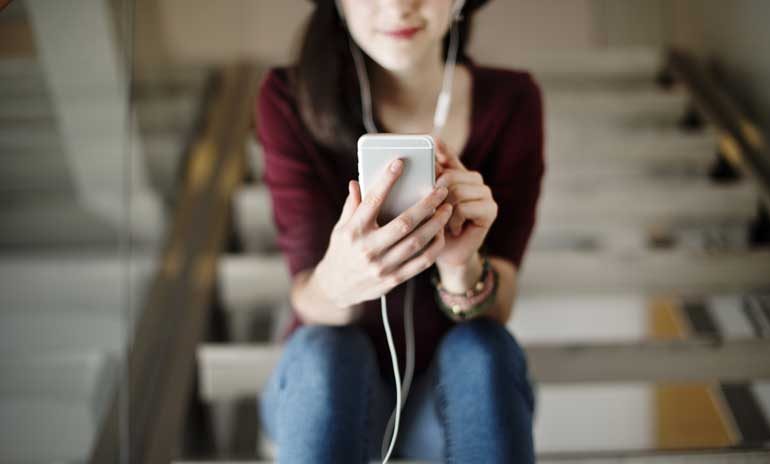 Vrouw luistert naar podcast op de trap.