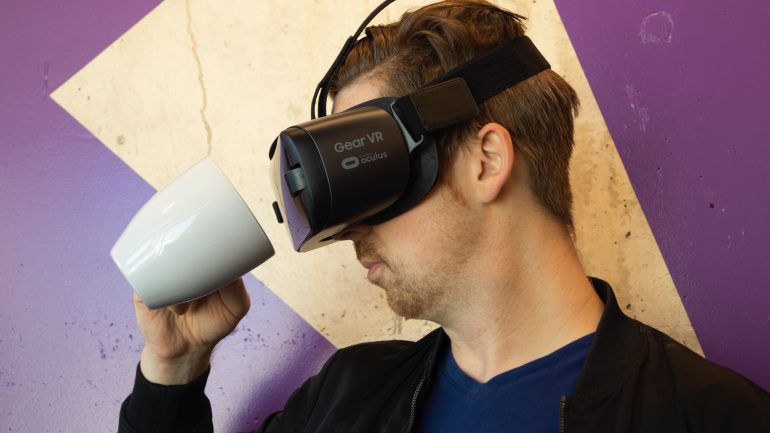 Foto van man met VR-bril die in een koffiemok kijkt