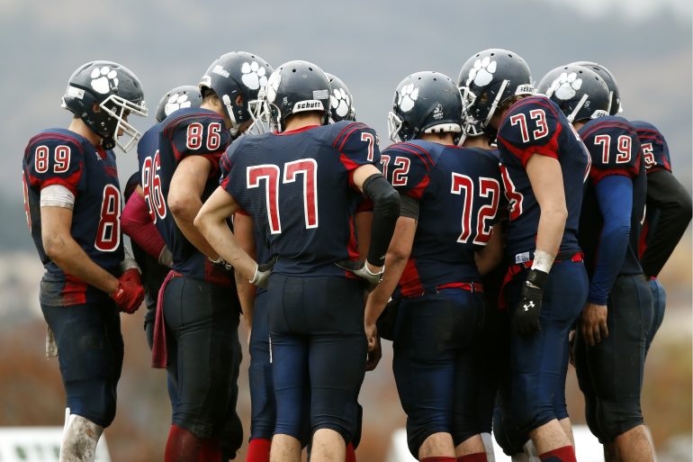 Foto van American football-spelers in overleg (een huddle).