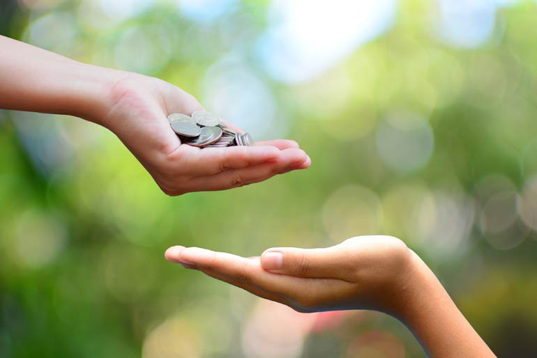 Hand geeft donatie geld aan andere hand.