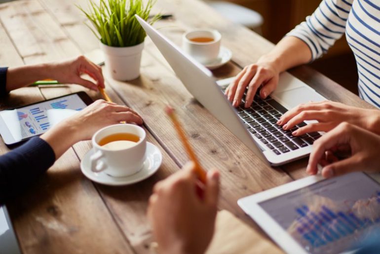 Mensen aan het werk op digitale werkplek met laptop en tablets. 