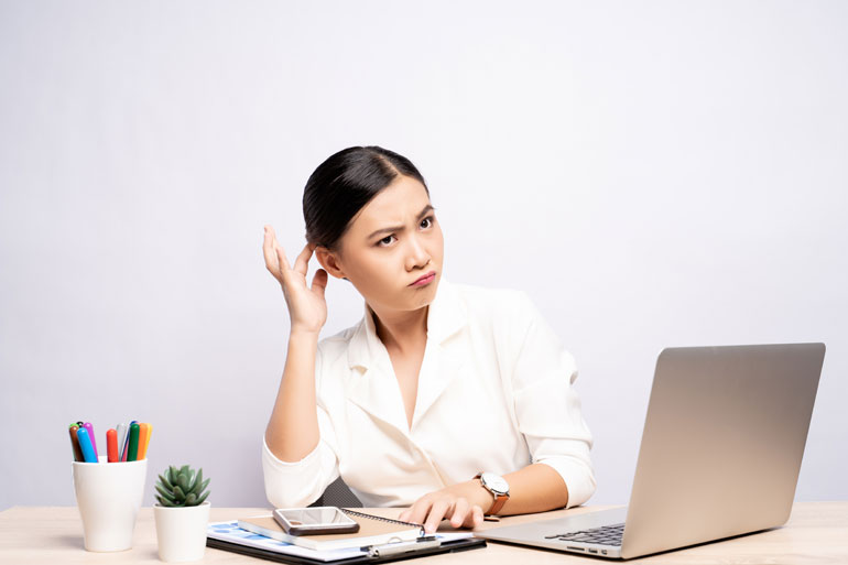 Vrouw denkt na bij laptop.