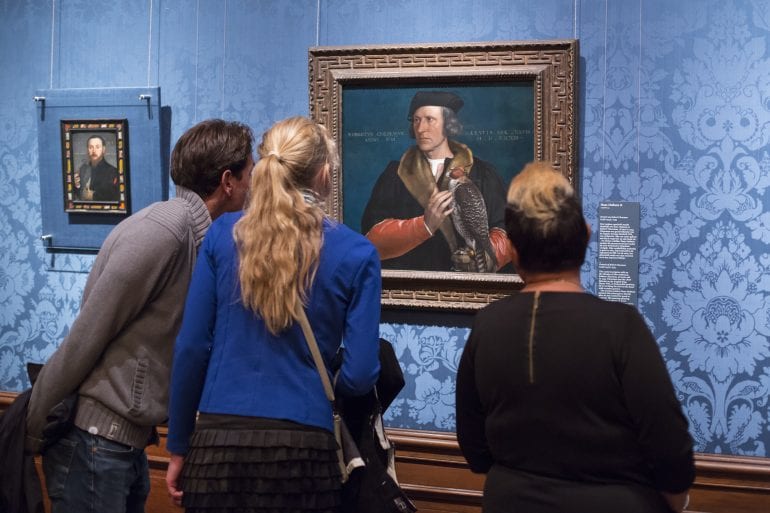 3 personen die naar een schilderij kijken.