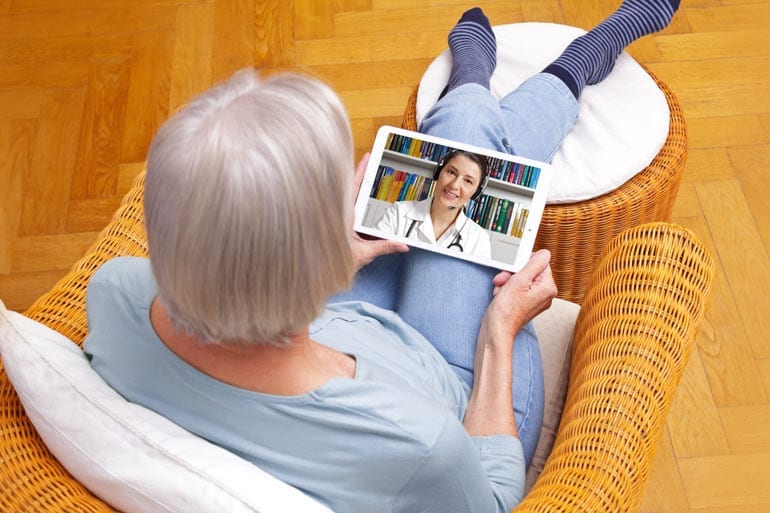 Oudere vrouw spreekt dokter via tablet.