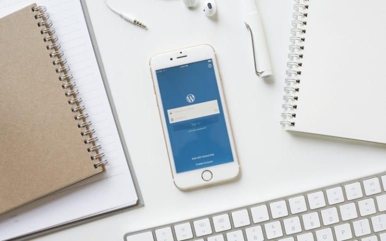 Bureau met notitieboekjes telefoon met WordPress-app toetsenbord oortjes en pen