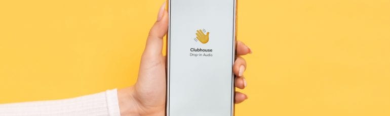 Iemand die een telefoon vasthoudt met de app Clubhouse in beeld.