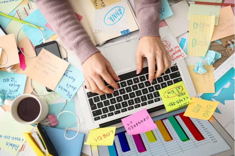 Vrouw werkt achter laptop en is overweldigd door alle taken.