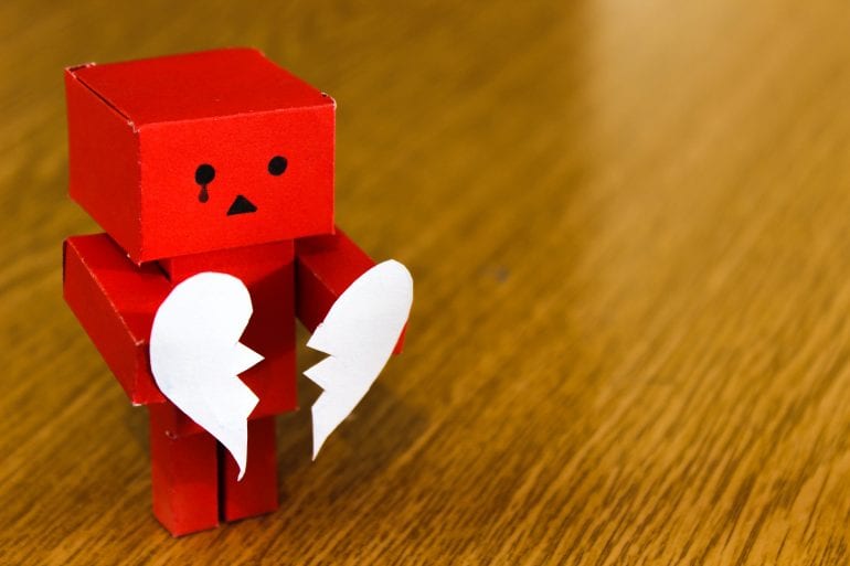 Een rood poppetje met een gebroken hart op tafel.