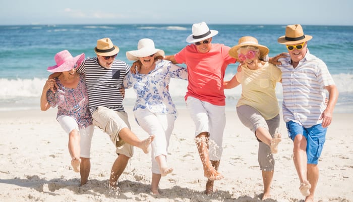 Oudere mensen die dansen op het strand, arm in arm