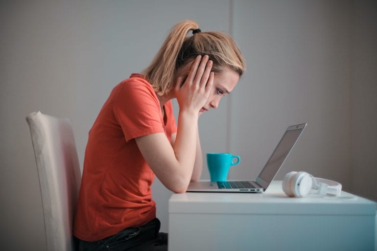 Vrouw kijkt verbaasd naar computerscherm.