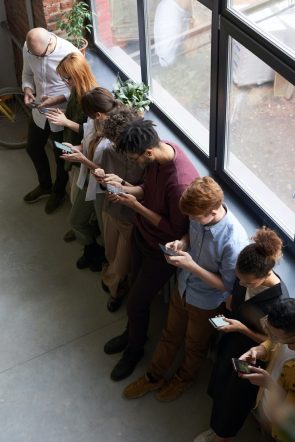 Foto van een groep personen die allemaal op hun smartphone kijken