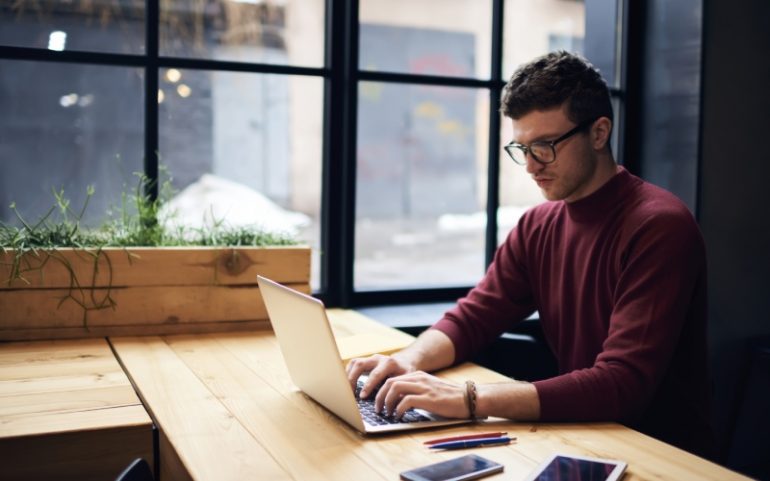 Man achter laptop bij artikel over duidelijke zakelijke teksten schrijven