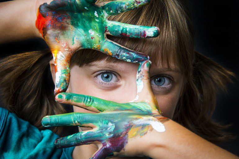 Creatief kind met verf op haar handen.