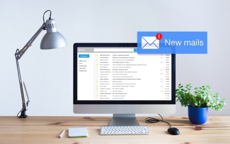 Bureau met computerscherm met e-mailprogramma ter illustratie van binnenkomend persbericht