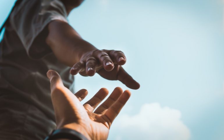 Reikende hand ter illustratie van compassievol leidinggeven