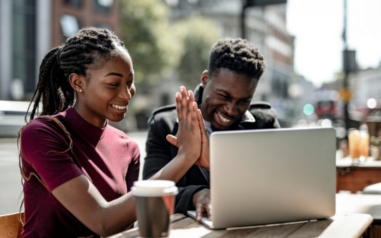 Copywriter collega's geven elkaar een high five achter een laptop