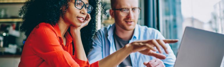 Collega's bespreken online marketing achter laptop