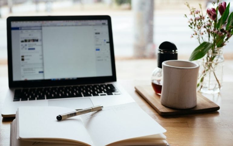 Laptop notitieboek en mok op tafel