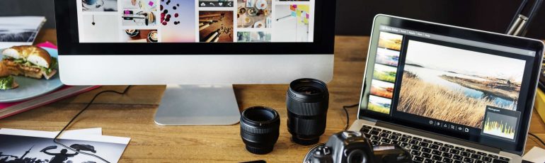 Bureau met fotoapperatuur en laptop en beeldscherm met foto's erop
