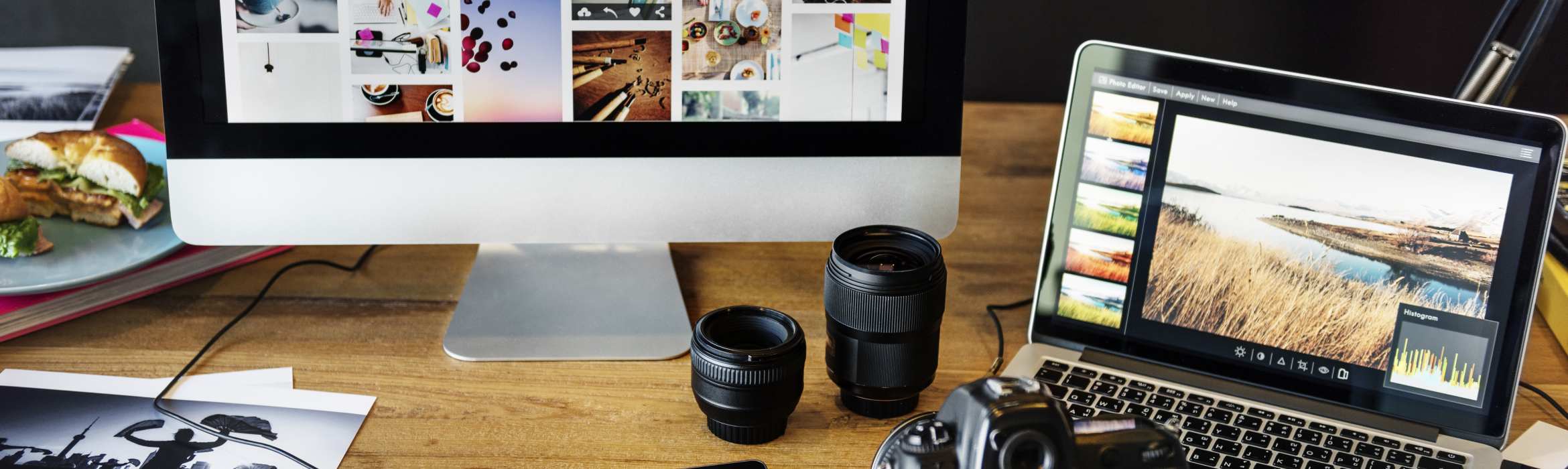 Bureau met fotoapperatuur en laptop en beeldscherm met foto's erop