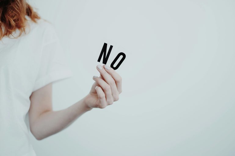 Persoon houdt twee letters omhoog die 'nee' vormen