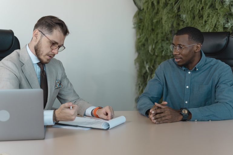 Twee mannen met elkaar in gesprek aan een grote tafel