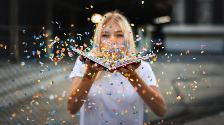 Vrouw blaast confetti uit boek