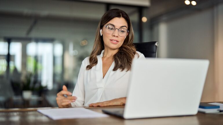 vrouw achter laptop met oortjes in