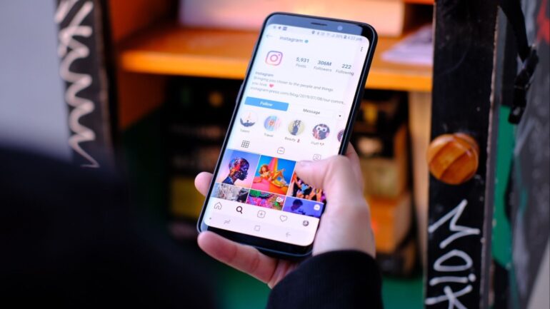 Persoon houdt een telefoon in de hand met het account van Instagram open.