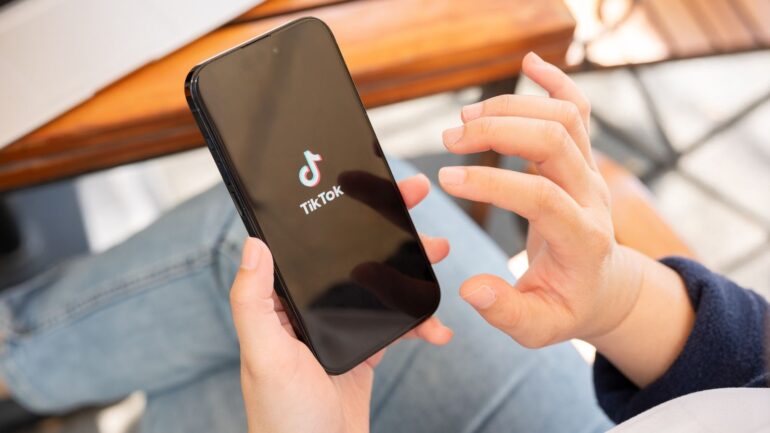 Persoon houdt telefoon vast met TikTok app.