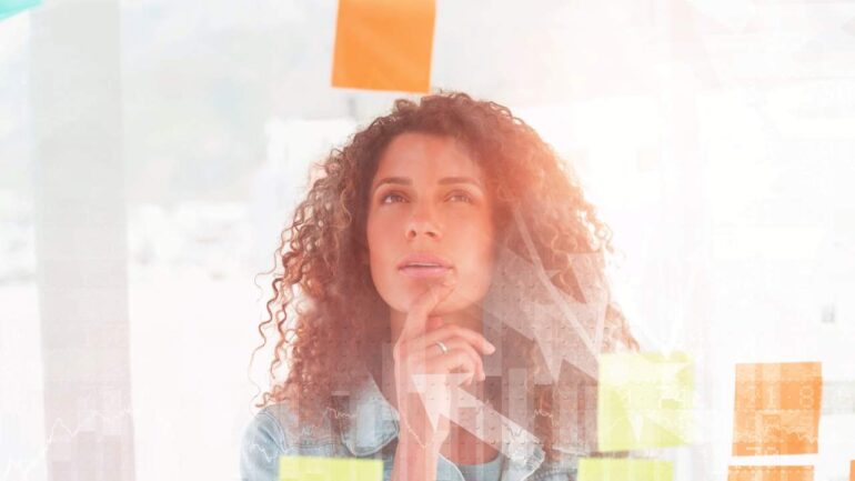Vrouw kijkt naar post-its op glazen wand ter illustratie van nadenken over AI integreren in werkproces