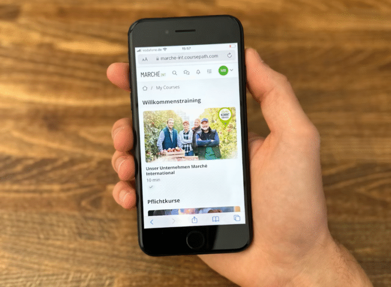 Smartphone toont onboarding-training van Marché International via mobiel LMS