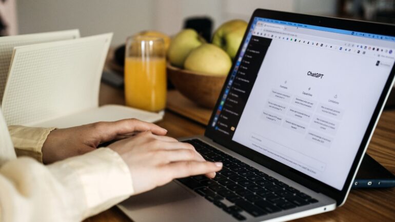Een vrouw achter een laptop met Chatgpt op haar scherm.