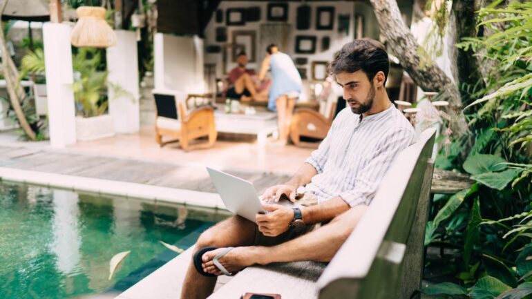 Zijaanzicht man met laptop aan zwembad