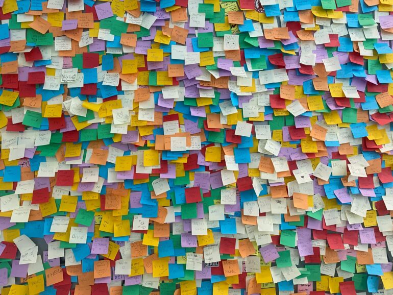 Decoratief beeld van heel veel gekleurde post-its met onleesbare teksten erop
