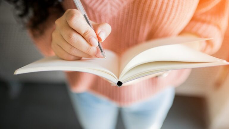 Vrouw die gaat schrijven in notitieboek bij artikel over maken van een shitlist