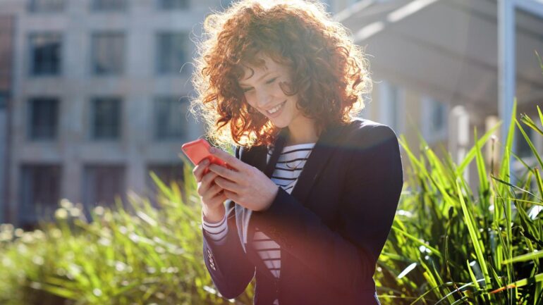 Zakelijke vrouw die op telefoon kijkt ter illustratie van social media aanpak bij gemeenten
